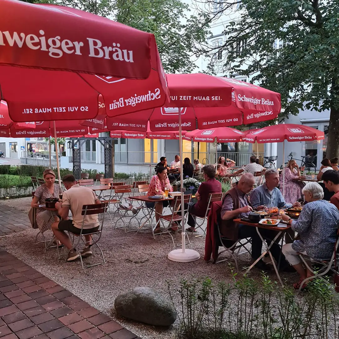 Blick in den gut besuchten Biergarten des Restaurants im Sommer.